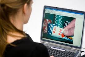 Kvinna framför dator med bild på hand som håller spelkort och spelmarker i bakgrunden